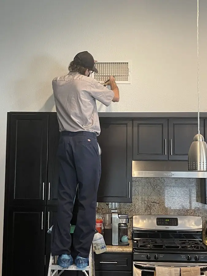 Technician inspecting an air vent during HVAC service in Winchester